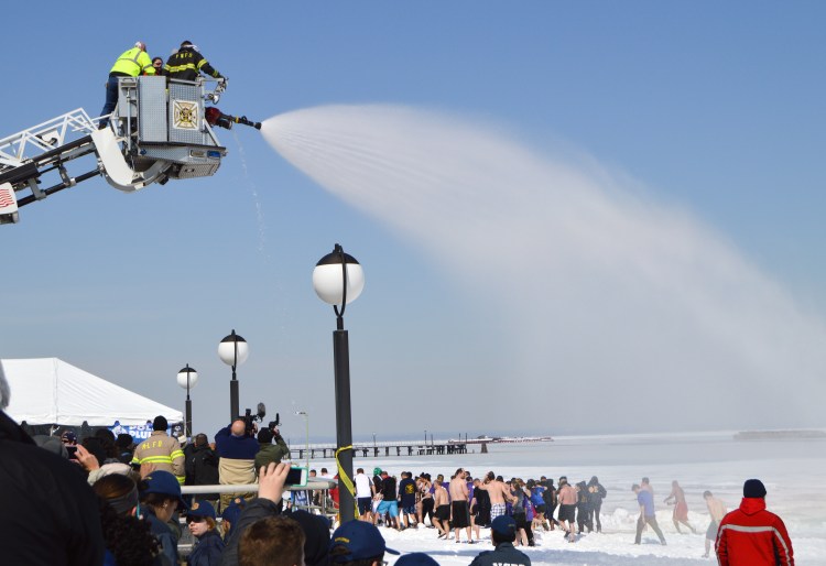 The Port Washington fire department sprays water on Polar Plunge volunteers.
